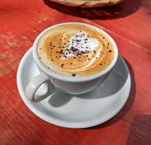 A latte in a white cup with a heart design.