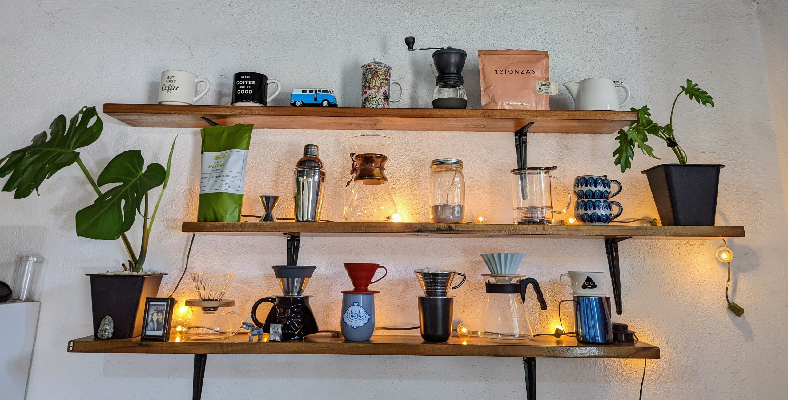 Wooden shelves containing different coffee makers and mugs.