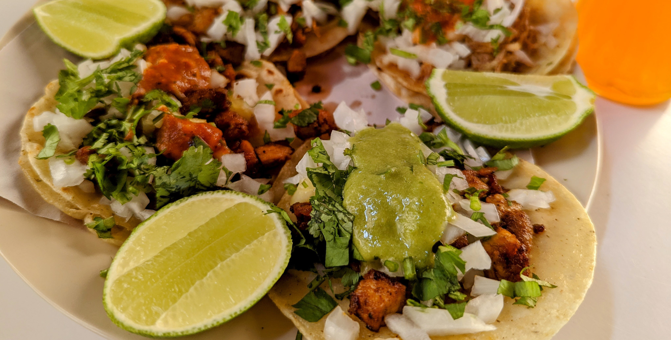 Tacos on a white plate with lime.