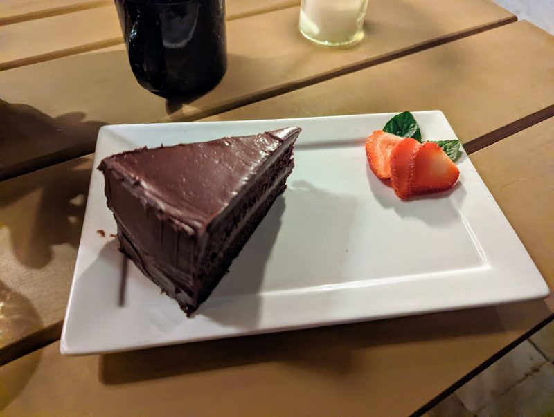 A slice of chocolate cake with sliced strawberries on a white plate. 