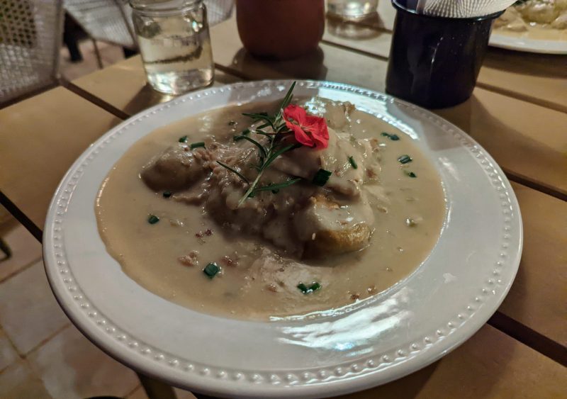 Ravioli in a cream sauce with a red flower on top.