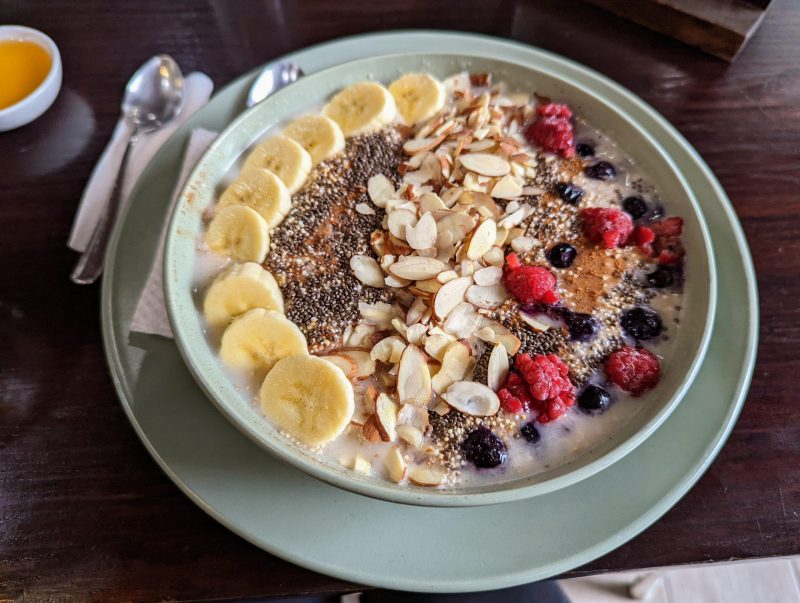 A bowl of oatmeal with banana, chia seeds, almond slices and berries on top. 