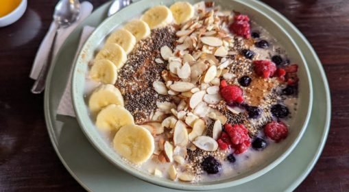 A bowl of oatmeal with bananas, berries chia seeds and almonds on top.