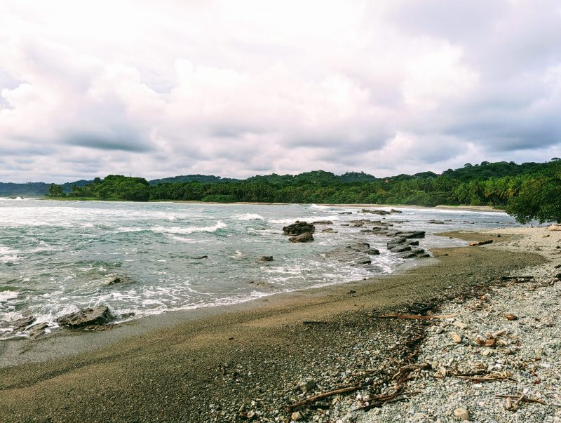 A beach with rocky sand and turquoise water. 